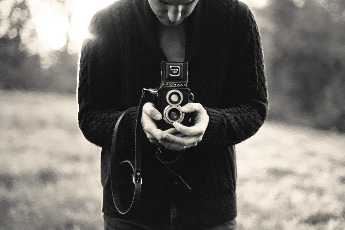 Persona sosteniendo una cámara fotográfica de dos lentes